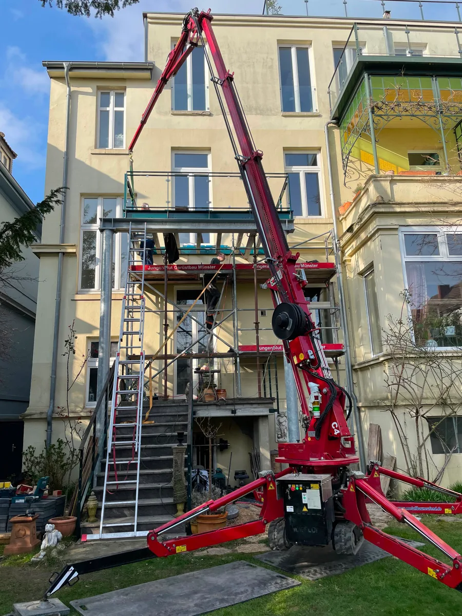 Kompaktkran hebt Bauteile an einer Altbaufassade in Münster
